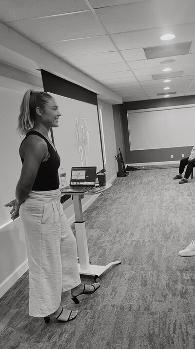 A female standing in front of an audience presenting on mental performance health