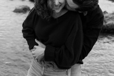 A person hugging their partner from behind and kissing their cheek 