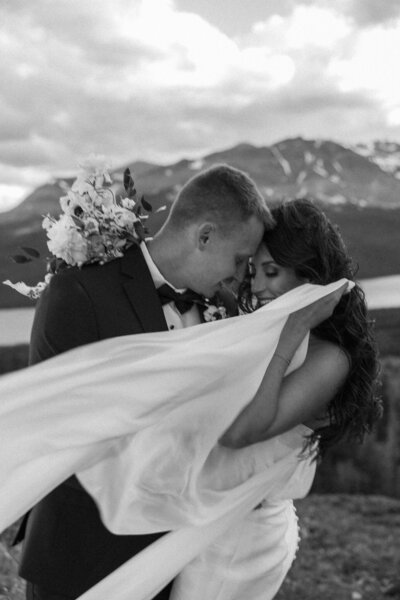 a couple snuggling up to each other surrounded by mountain views