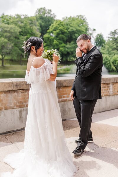 bride and groom emotional candid moment in park with water fountain during wedding photo session in new york