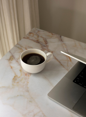 Coffee and laptop on marble desk styled for a faith-based creative agency