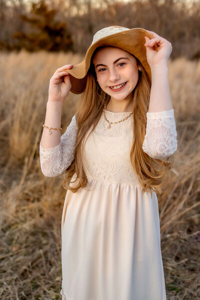 A girl is standing in a field wearing a black and silver prom dress. She is posing for family photos.