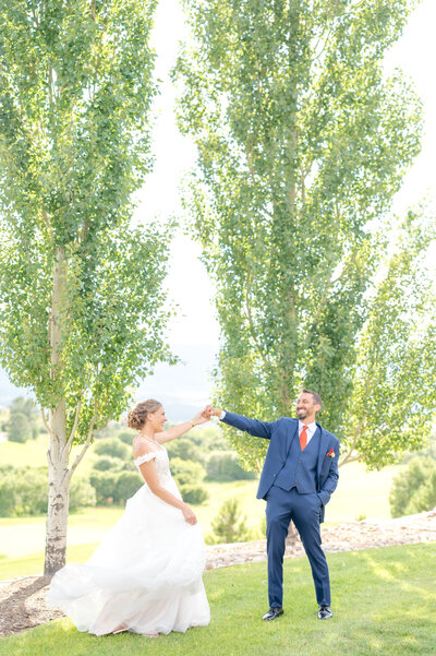 Groom holding his bride's hand in air while she is swishing her dress back and forth on their wedding day