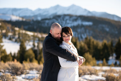wedding couple walking hand and hand with a mountain scene behind them including a gondola overhead