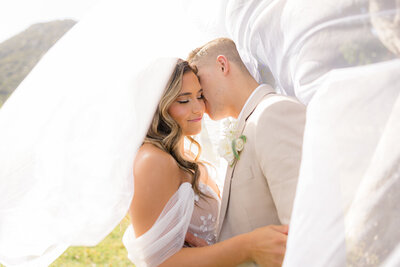 groom kissing bride on the cheek under her veil