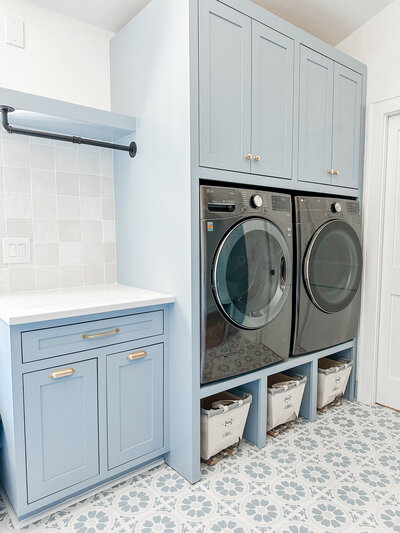 Coastal laundry room with blue cabinetry and floral tile.