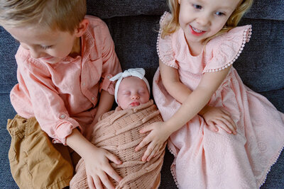 Newborn baby being held by big brother and sister during an in home lifestyle photoshoot
