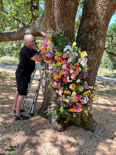 Dave of Flowers and Thyme works on a floral installation on a tree.