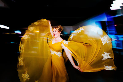 A bride dancing at the reception at the Toledo Zoo as her yellow wedding gown flows in the air