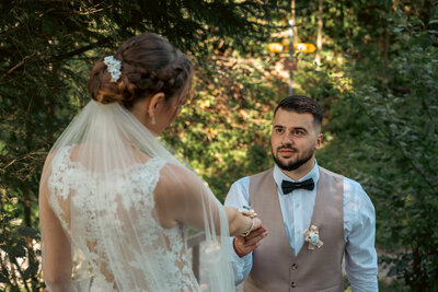 Der Bräutigam schaut liebevoll seine Braut an, hält zärtlich ihre Hand und drückt seine Gefühle in diesem herzlichen Moment aus.