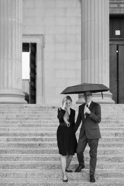 A couple embraces the weather and grabs an umbrella for their engagement photos