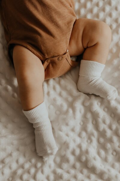 Baby laying down wearing a onesie and socks