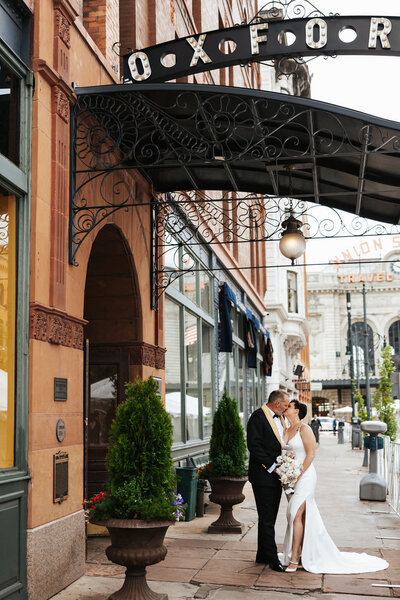 A wedding couple kissing on a city sidewalk