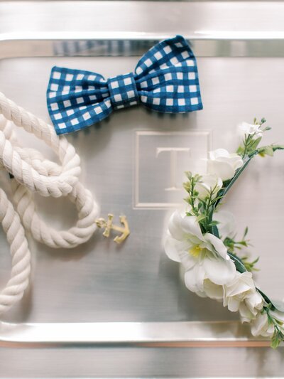 Wedding flatlay with bowtie, florals, and anchor charm