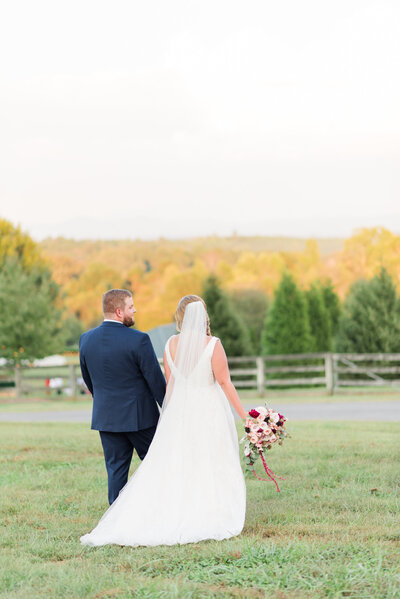 bride and groom walking in a field