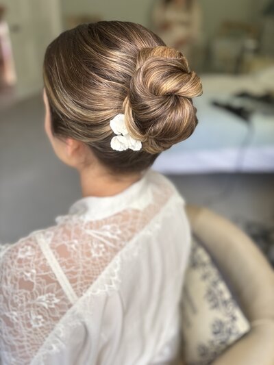 Sleek mid bun hairstyle with flower hairpin, Avington Park Wedding