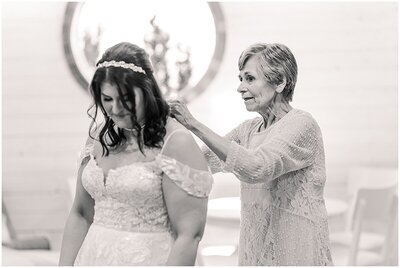 black and white photo of grandma putting a necklace on the bride in the getting ready suite