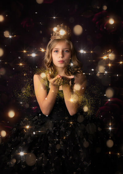 girl-in-studio-arlington-tx-blowing-glitter-wearing-black-dress-with-gold-crown