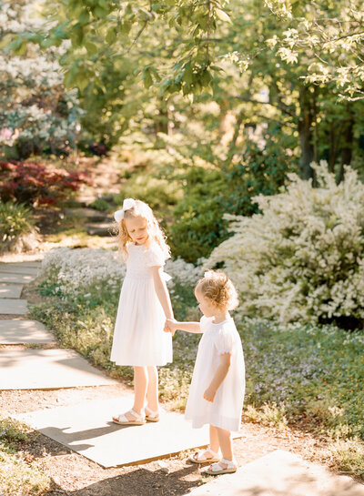 Photo of sisters holding hands in the gardens of Raulston Arboretum. Image by Raleigh Family Photographer A.J. Dunlap Photography.