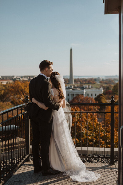 Bride and Groom Embrace on balcony of The Hay Adams for their wedding with DC in the background