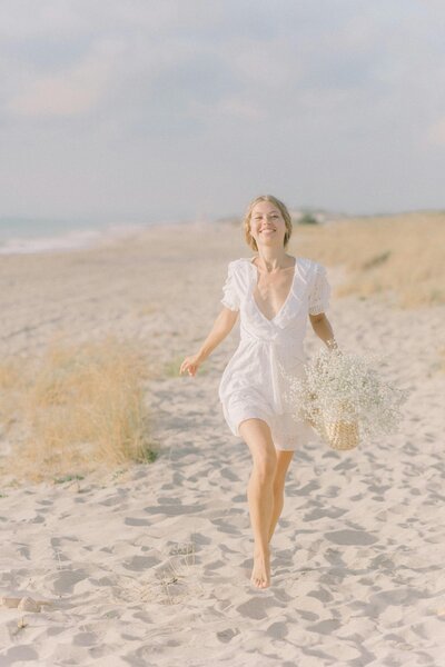 young woman running on beach with flowers in hand