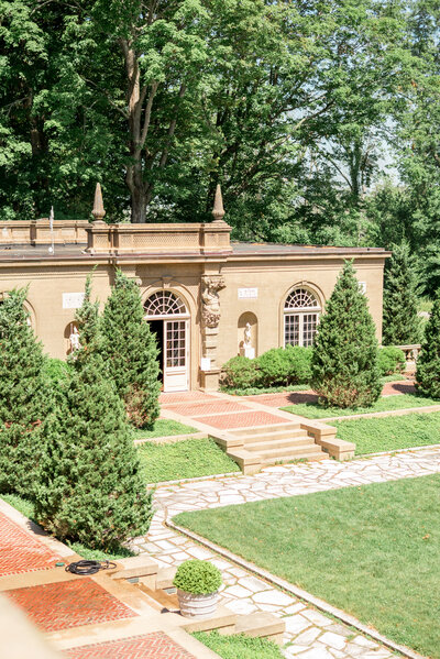 A romantic garden courtyard at Castle Hill featuring elegant stone architecture, arched windows, and lush landscaping — ideal for portraits or cocktail hour at this historic Ipswich estate.
