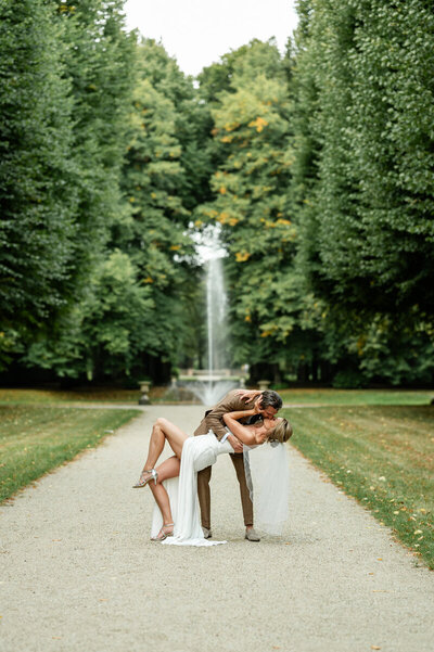Fotografie van een huwelijk voor het kasteel waar de bruidegom de bruid kust.