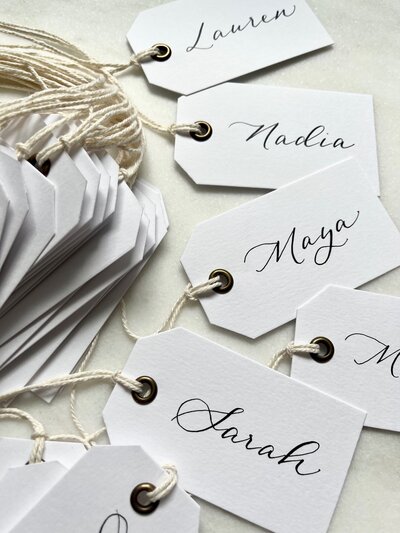 White gift tags with grommet and name in black ink calligraphy.