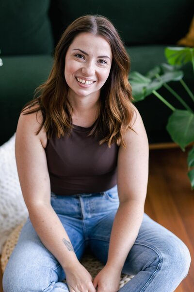 Isobel sitting on the floor and smiling for the camera during her brand photos