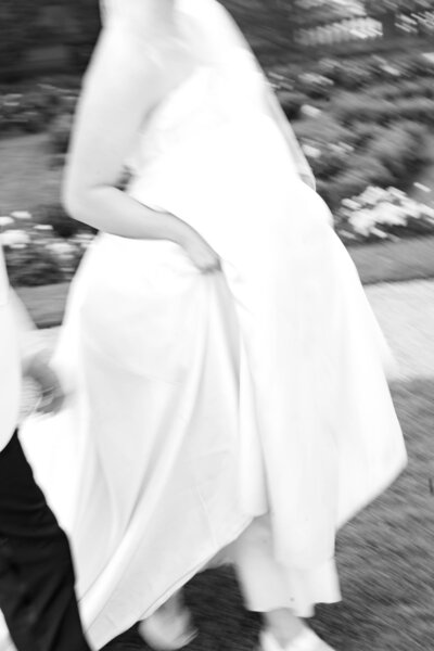 Glen Manor House | Blurred black-and-white image of a person in a flowing dress walking on grass. Soft focus creates a sense of movement and elegance.
