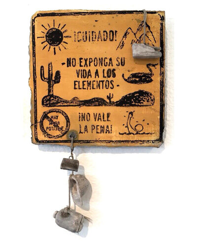 A caution sign made out of ceramic hangs on a wall, warning against the dangers of extreme elements that one can face if crossing the border