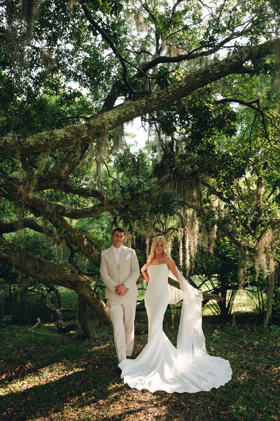 Bride and groom pose under a tree in Oahu