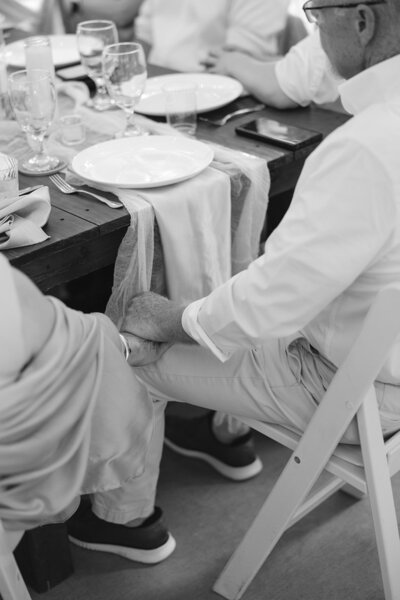 Black and white image of couple holding hands at Nashville wedding dinner