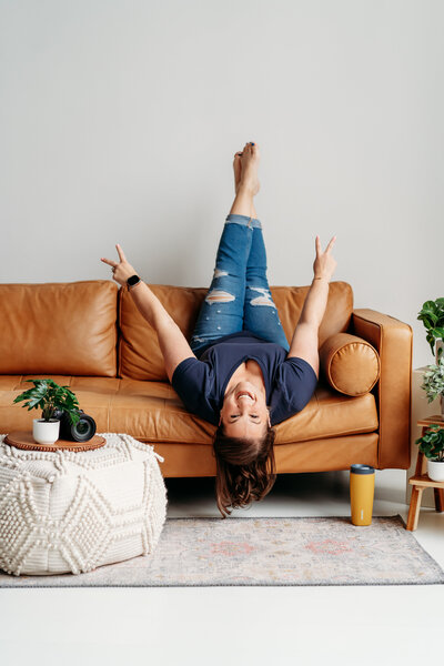 Woman laying on leather couch with feet in the air.