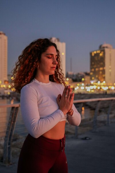A woman standing with hands at heart center practicing her healing with chakras