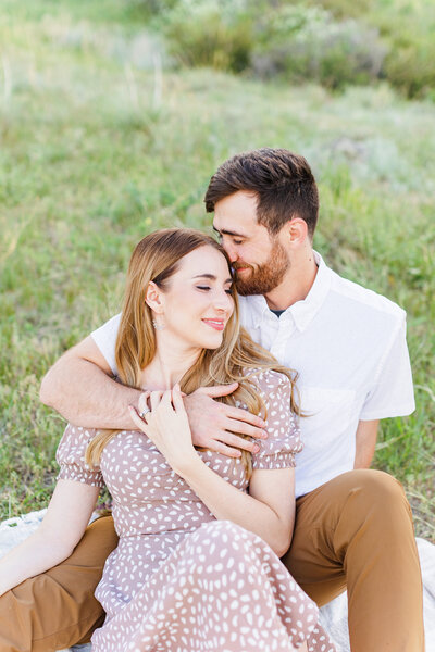 engaged couple sitting in a field