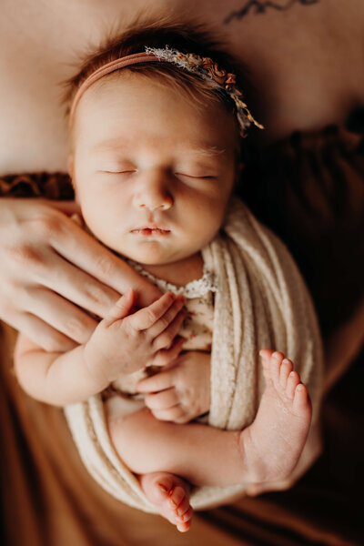 iconic swaddled newborn holding her mom's hand