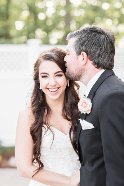 Wedding portrait of groom kissing bride