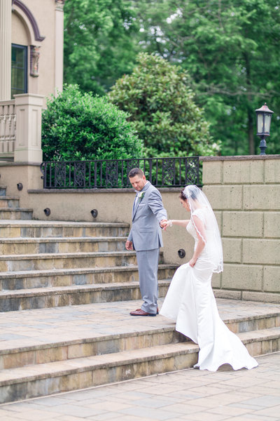 Groom helping bride walk up the steps