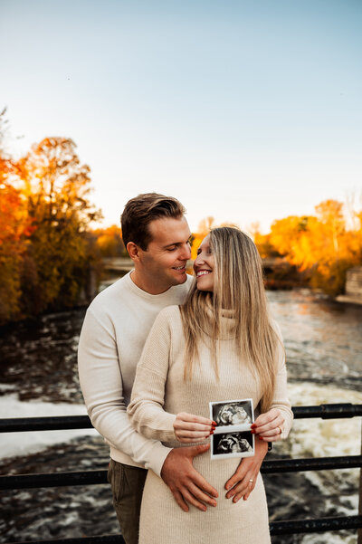 Family sitting together among colourful autumn leaves during Ottawa fall mini session.