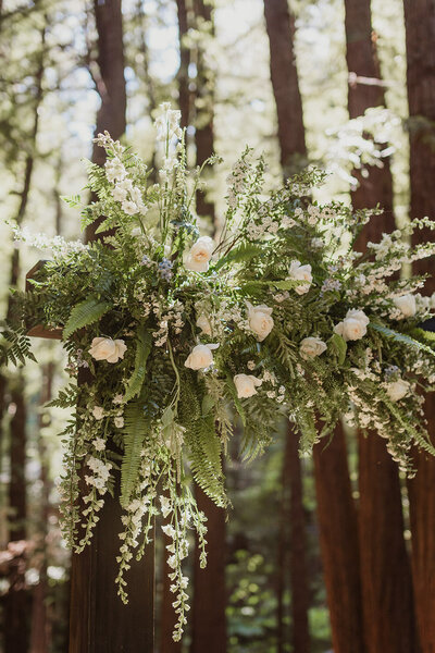 Forest wedding arch decorated with ferns and white roses