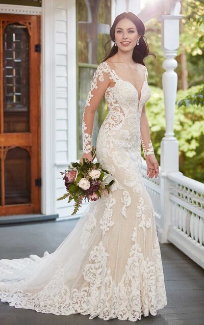 SHEER FLORAL CREPE WEDDING DRESS WITH ORGANIC TRAIN A radiant floral masterpiece, this wedding dress style from Martina Liana is a stunner at every angle. A sheer bodice graces the top of this gown with translucent side panels extending over the hips in a tapered formation, elongating the frame. A mix of organic florals, and bugle beads grow over the fabrics for a sheer, feminine allure and a hint of shimmer—falling over the waistline onto the luxe crepe fabric that gently hugs the curves. An organic neckline mirrors a low organic V-back, adjoined by a zipper enclosure topped with fabric-covered buttons that run the length of the fit-and-flare silhouette—all the way to the hem of the incredibly detailed, sheer scallop train featuring a myriad of floral appliqués for a breathtaking bridal finish.