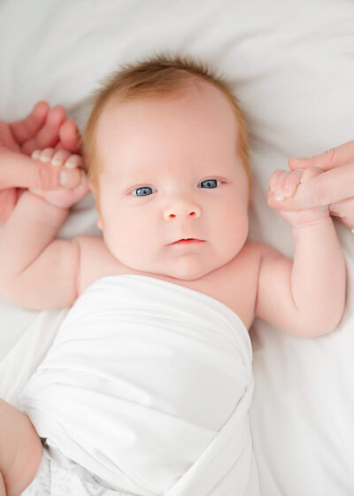 Newborn baby wrapped in white swaddle sleeps during Atlanta Newborn Photography Session.