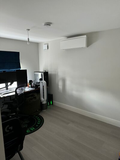 Image of a wall-mounted air conditioning unit installed in a modern living room, showcasing a sleek and discreet design.