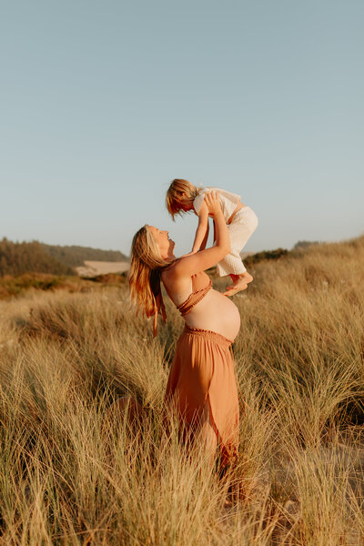 A mother with her toddler in a field at sunset