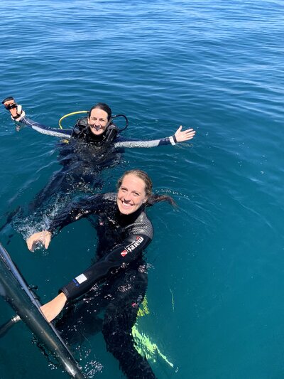 2 divers in the water smiling after surfacing post-dive.