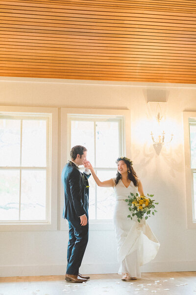 Groom kisses his brides hand as they dance inside a church with natural light
