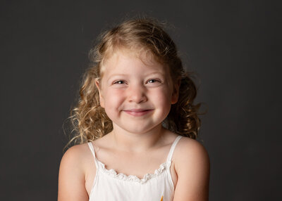 A school portrait of a curly-haired girl with a big smile.