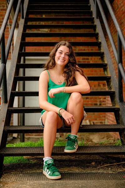 Emma, a cuthbertson high school senior, poses in downtown waxhaw wearing jean shorts, a green top and matching green sneakers