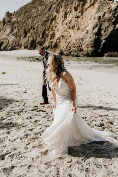BRIDE AND GROOM WALKING ALONG BIG SUR BEACH DURING CALIFORNIA ELOPEMENT